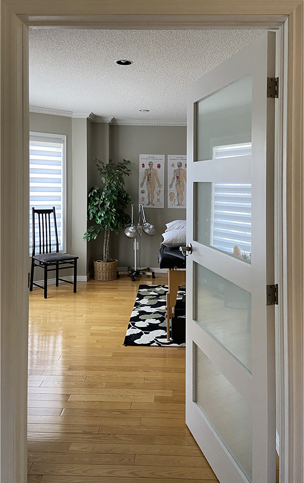 photograph looking through an interior doorway into the clinic, a comfortable room with hardwood floors and brightly lit with large windows